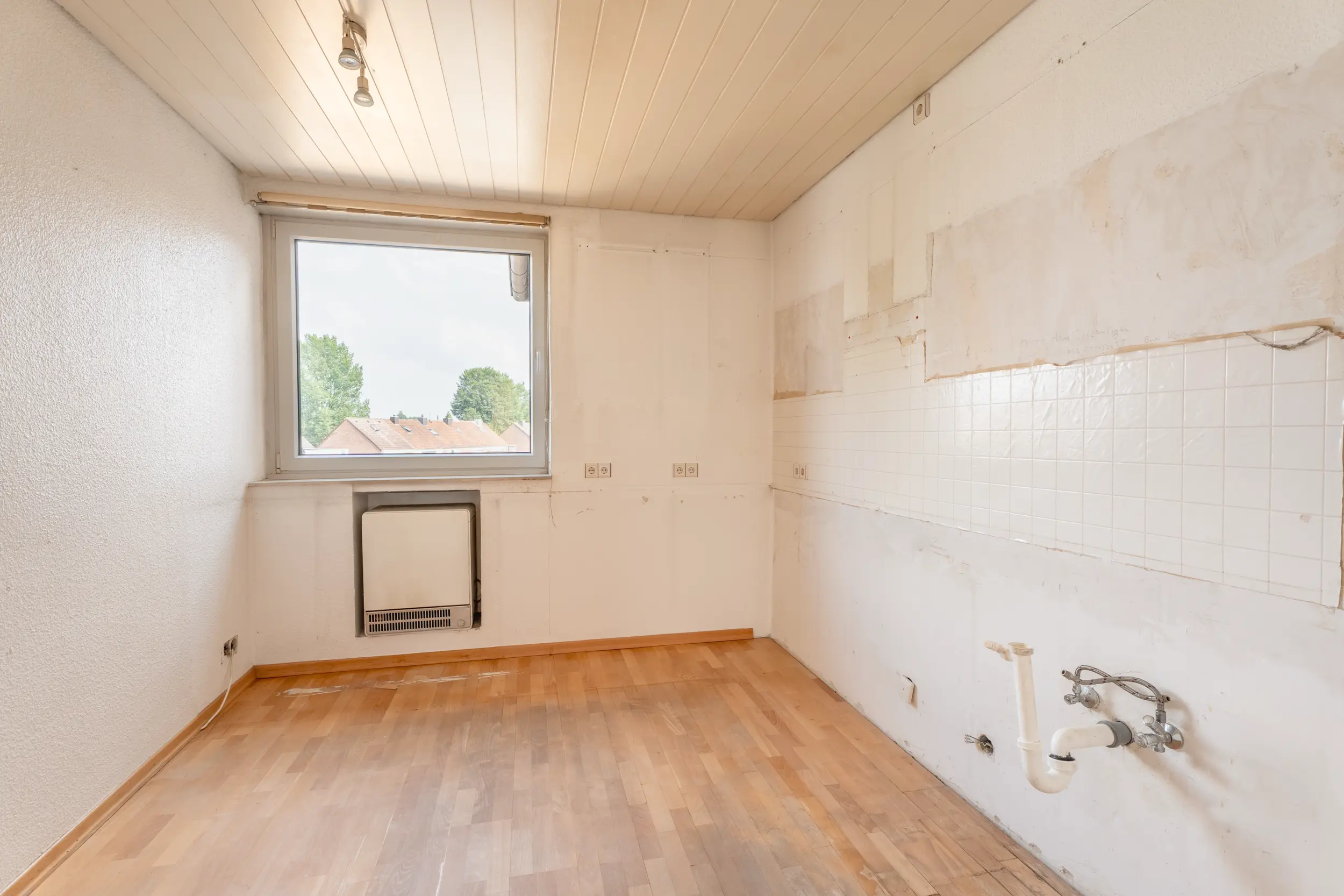 Separate Küche der Dachgeschosswohnung in Nordhorn-Blanke ohne Einbauküche, mit Fenster, Laminatboden und vorhandenen Küchenanschlüssen.
