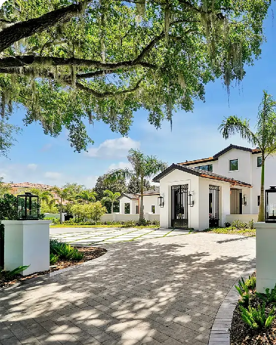 A beautiful home with a driveway surrounded by lush palm trees under a clear blue sky.