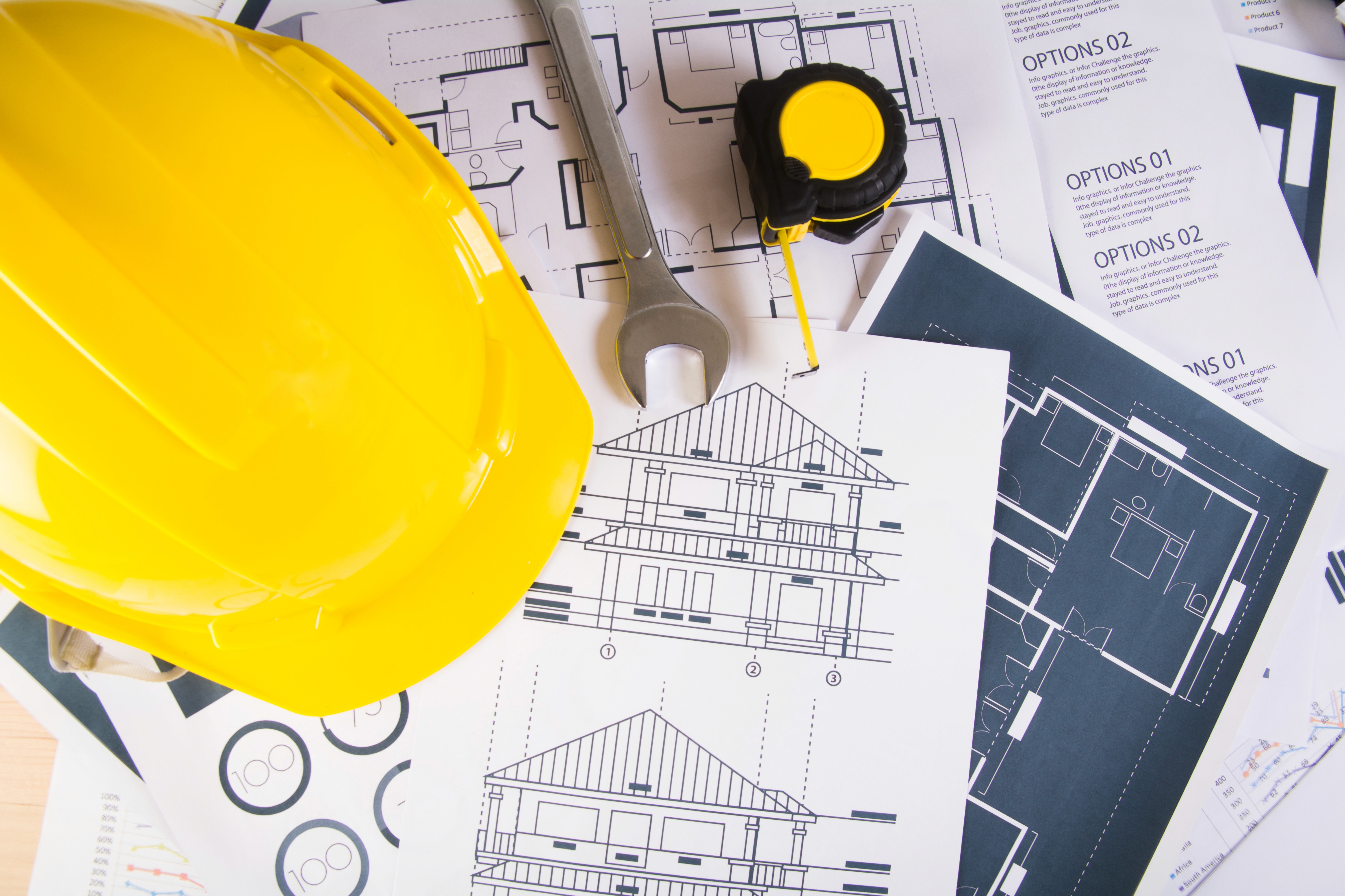 Casque de sécurité jaune et plans de bâtiment sur une table