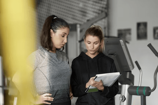 High school student conducting sports science research with a PhD mentor reviewing biomechanics data on a laptop