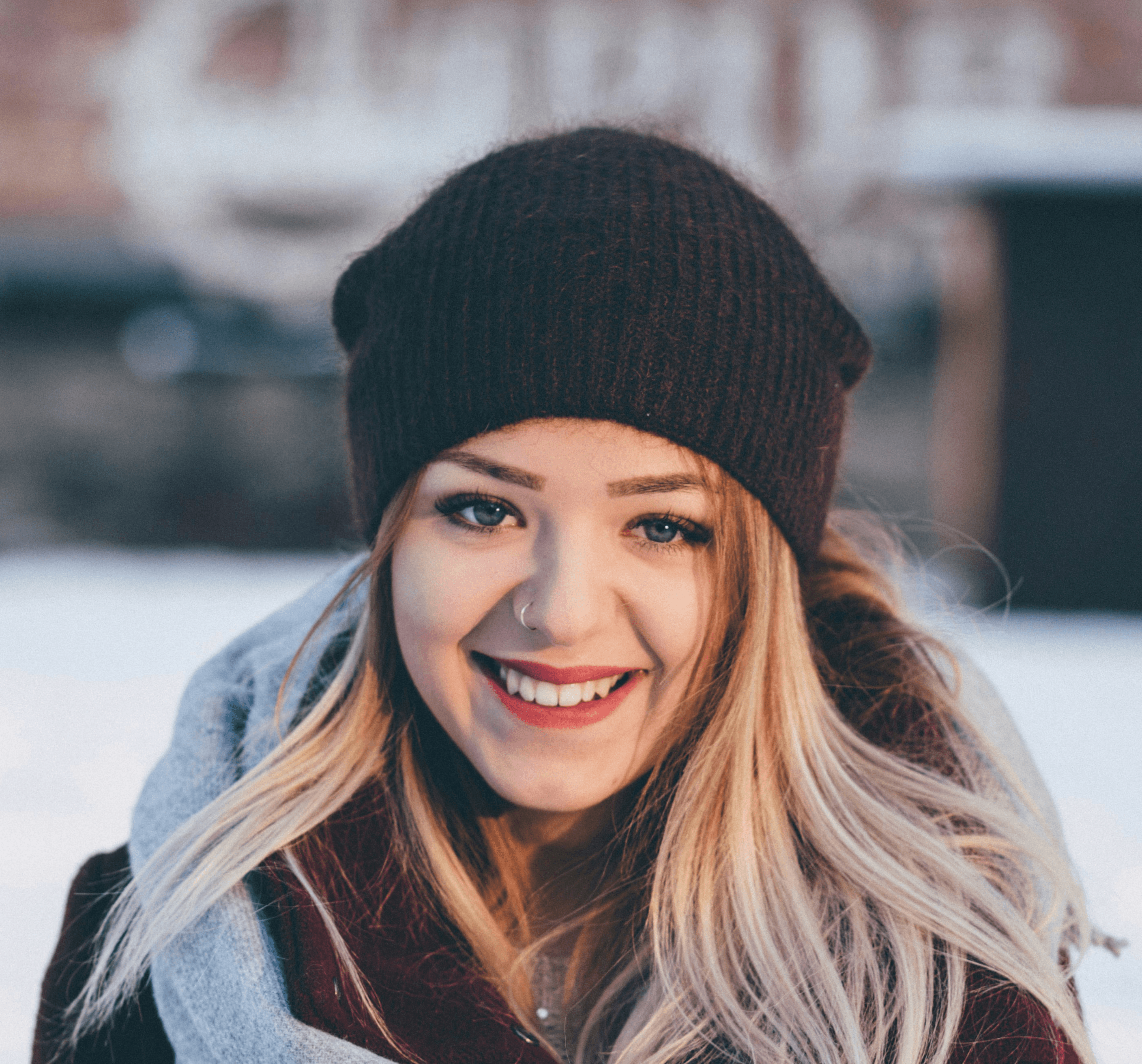smiling woman wearing brown scarf and maroon coat on snow field