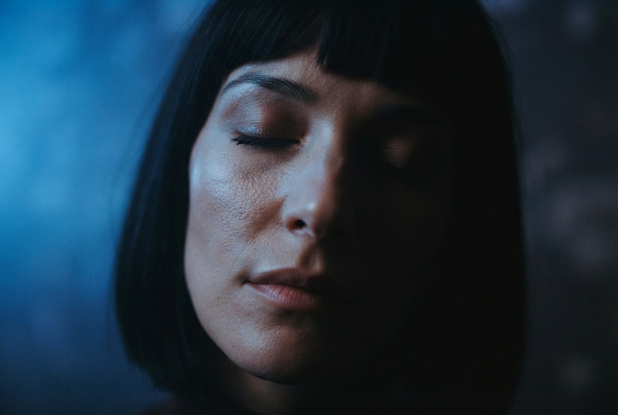 A face half-lit in blue, eyes closed