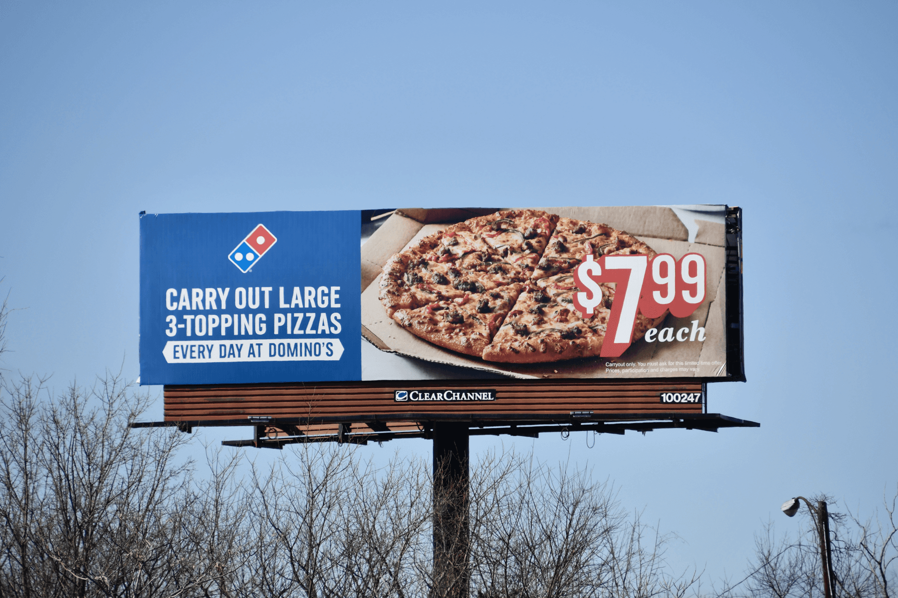 a man walking down a street past a large poster