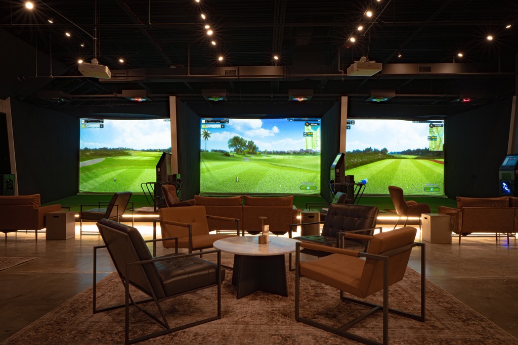 an interior of flogolf lounge. golf simulators screens chairs and table