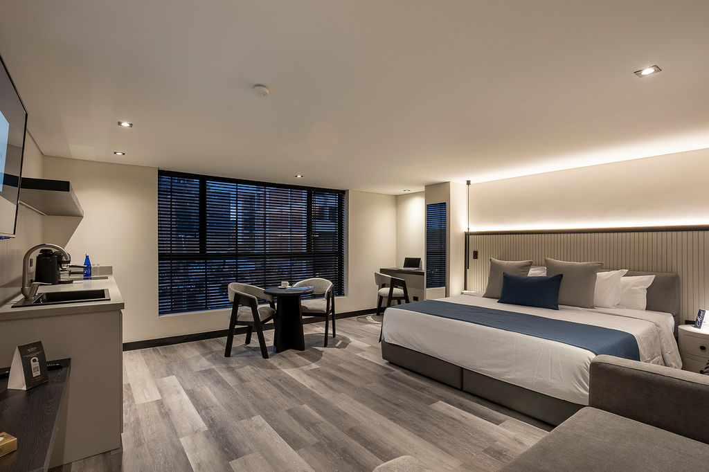 Habitación de lujo con cama king Medellín en Altus Hotel, con ventanales insonorizados y diseño elegante en Laureles.