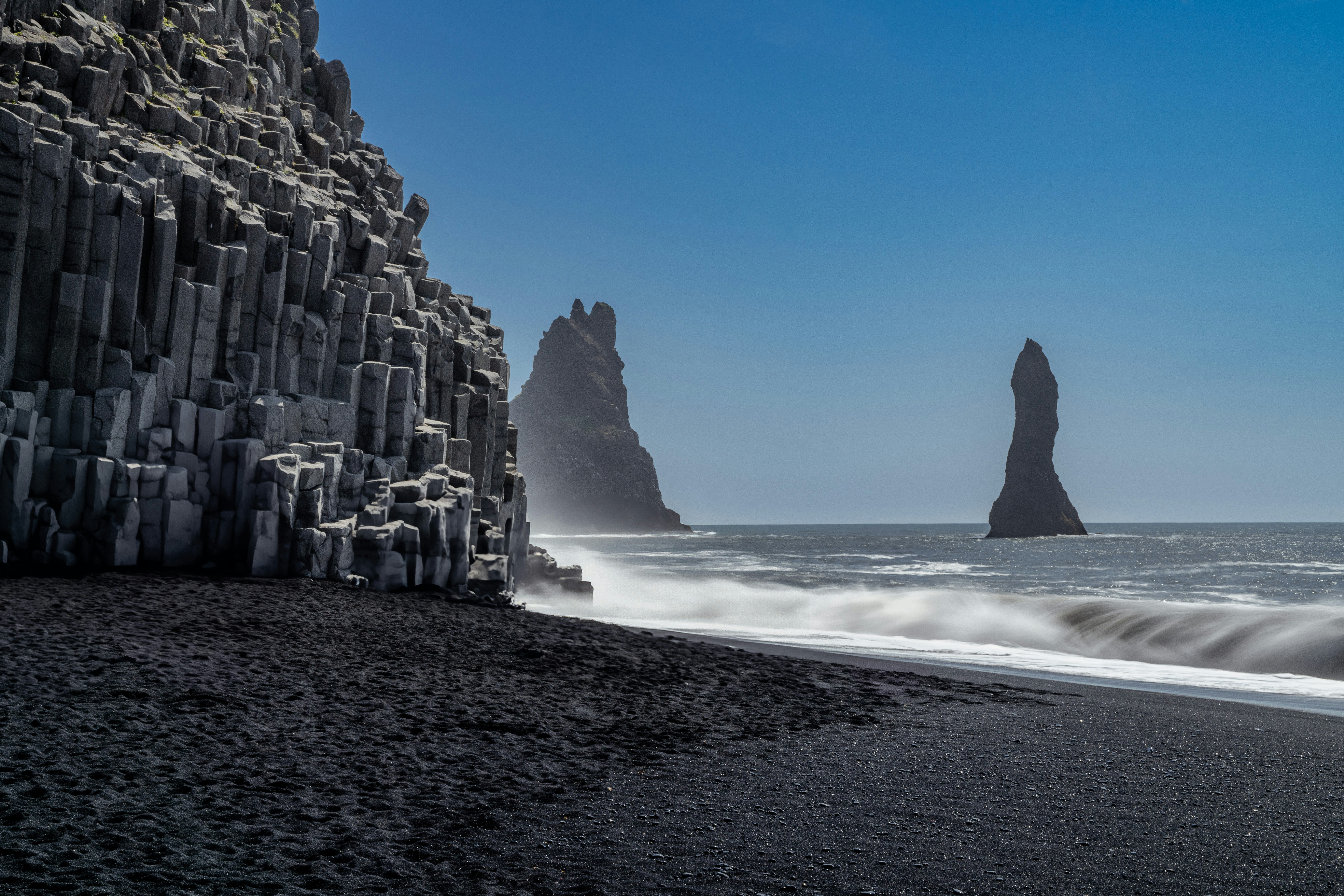 Basalt columns and sneaker waves at Reynisfjara Black Sand Beach, Iceland.