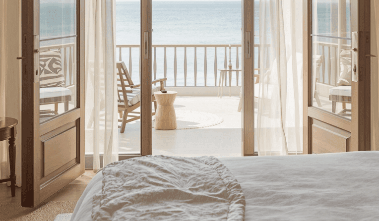 Luxurious open living space with pool, palm trees, and ocean view beyond.
