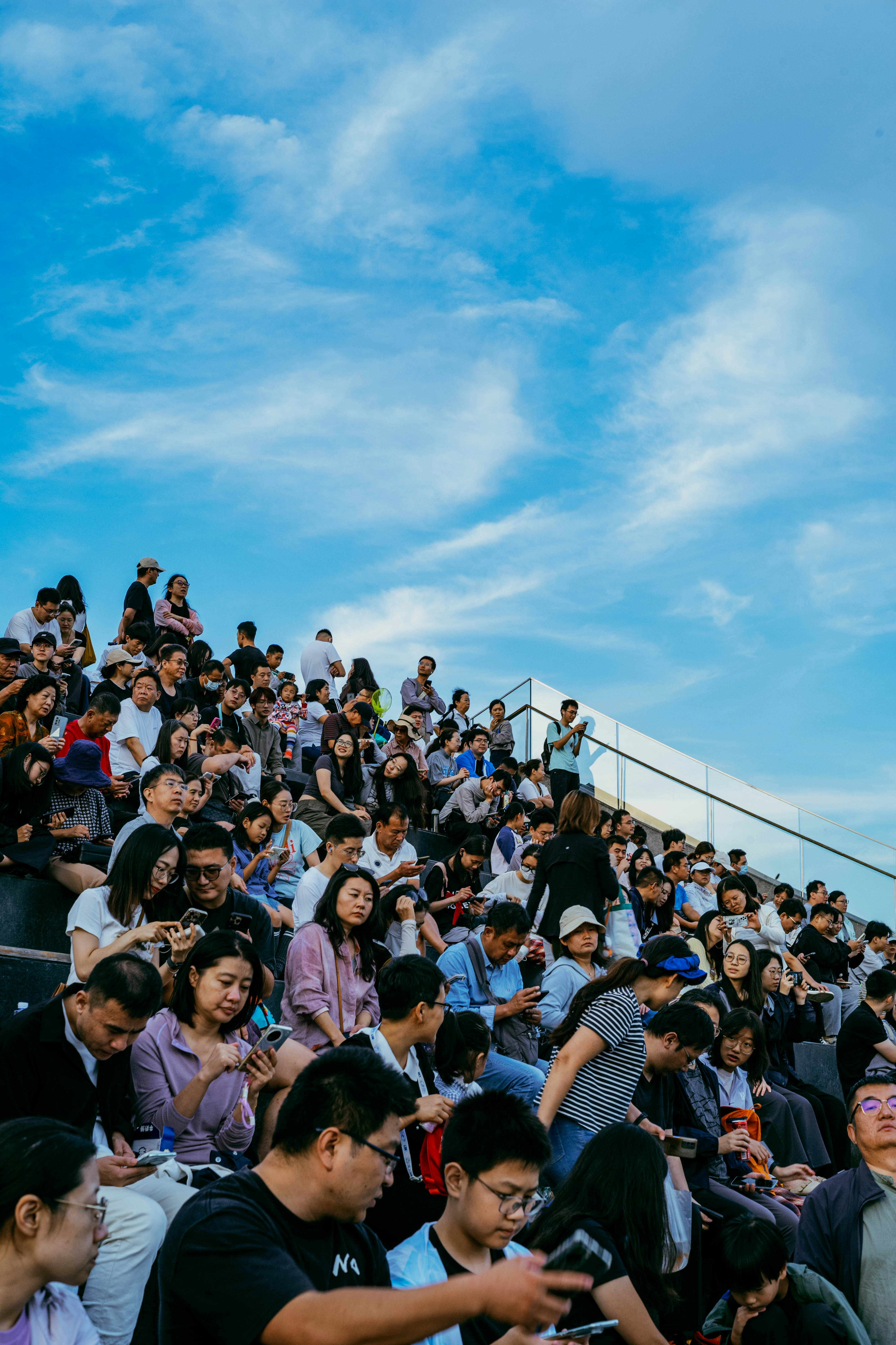 Crowd of people sitting on stadium steps under sky