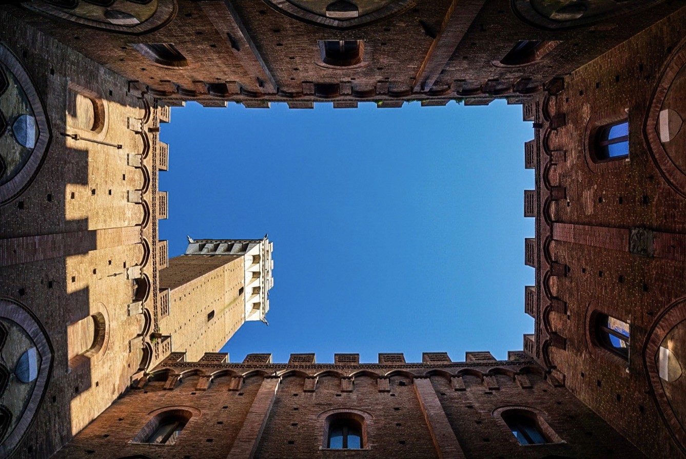 View of a vivid blue sky framed by the square opening of historic brick walls and tower, photographed by Janice Chen.