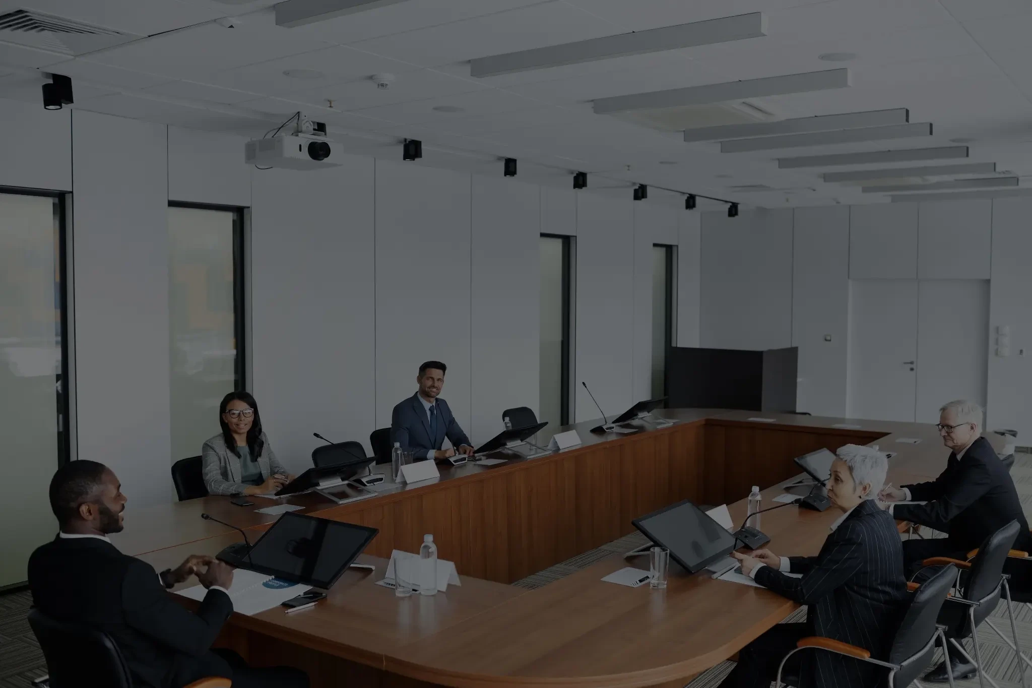 Business professionals seated around a conference table in a modern meeting room.