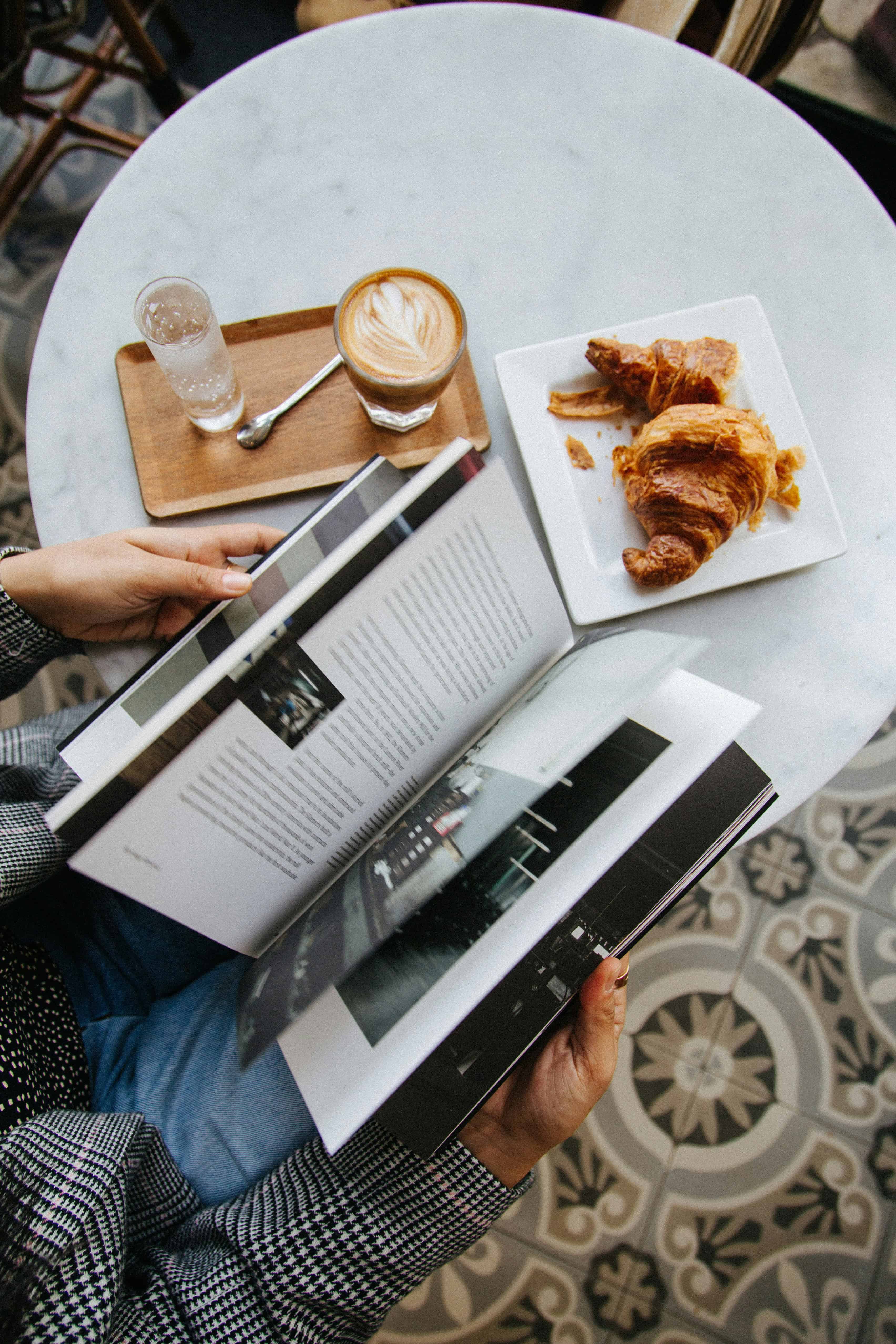 Relaxing breakfast with coffee and croissant reading a magazine