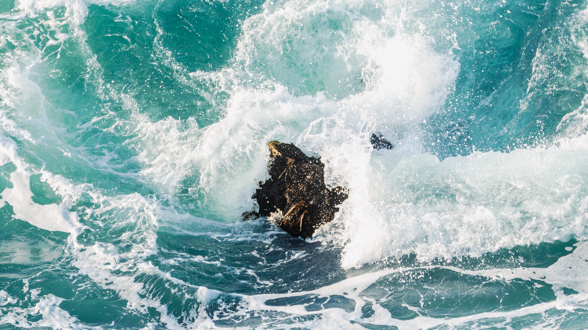 waves crashing against a rock at sea