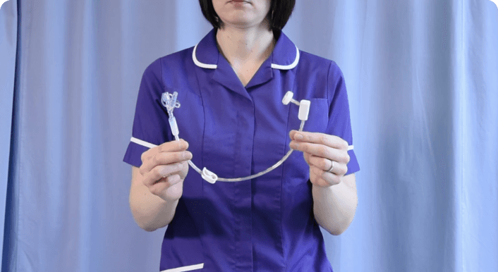 Nurse holding medical tubing device against curtain backdrop.