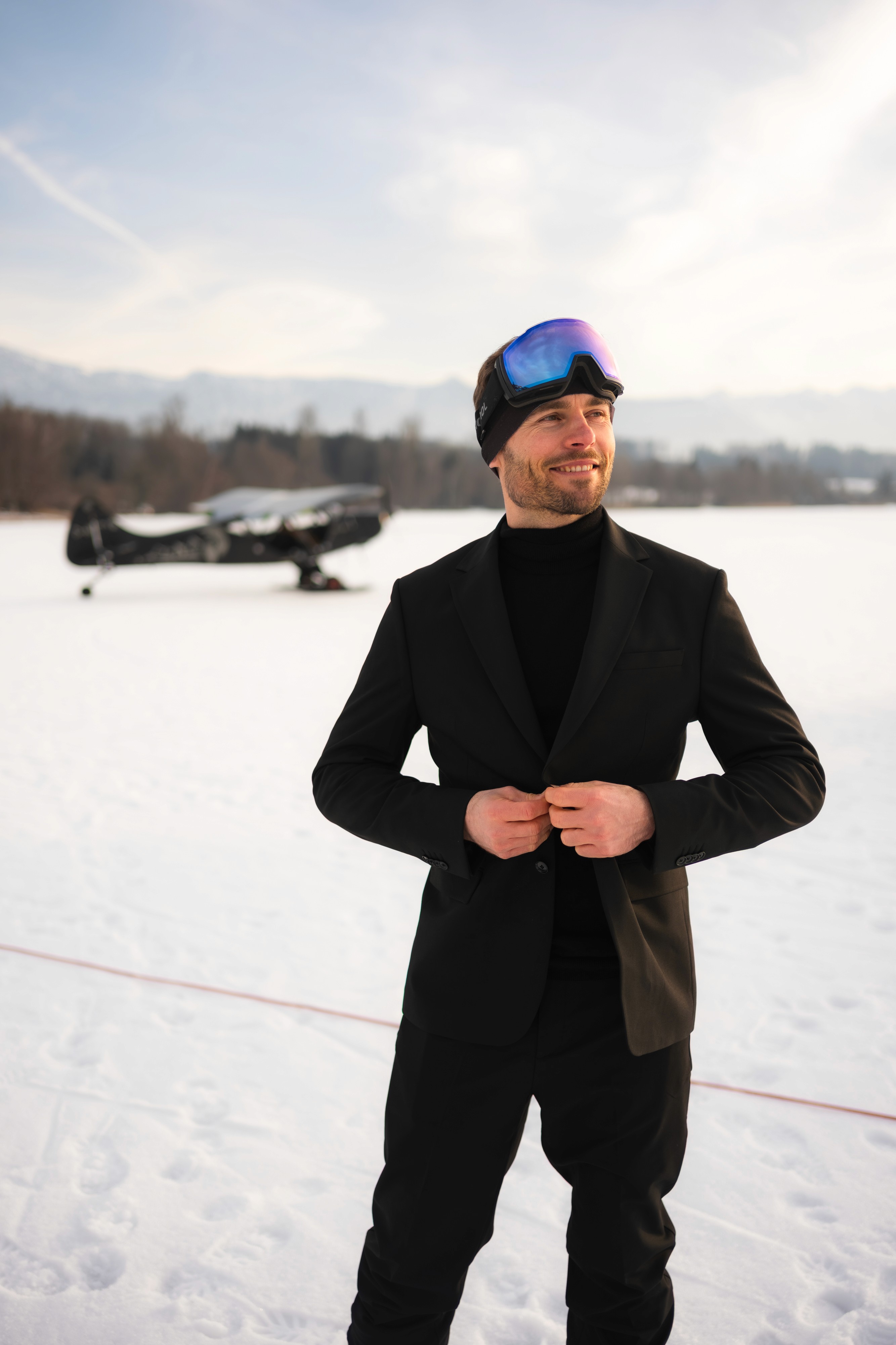 Tobi Deckert in the Shaping New Tomorrow suit with ski goggles in front of the Piper on Lake Riegsee