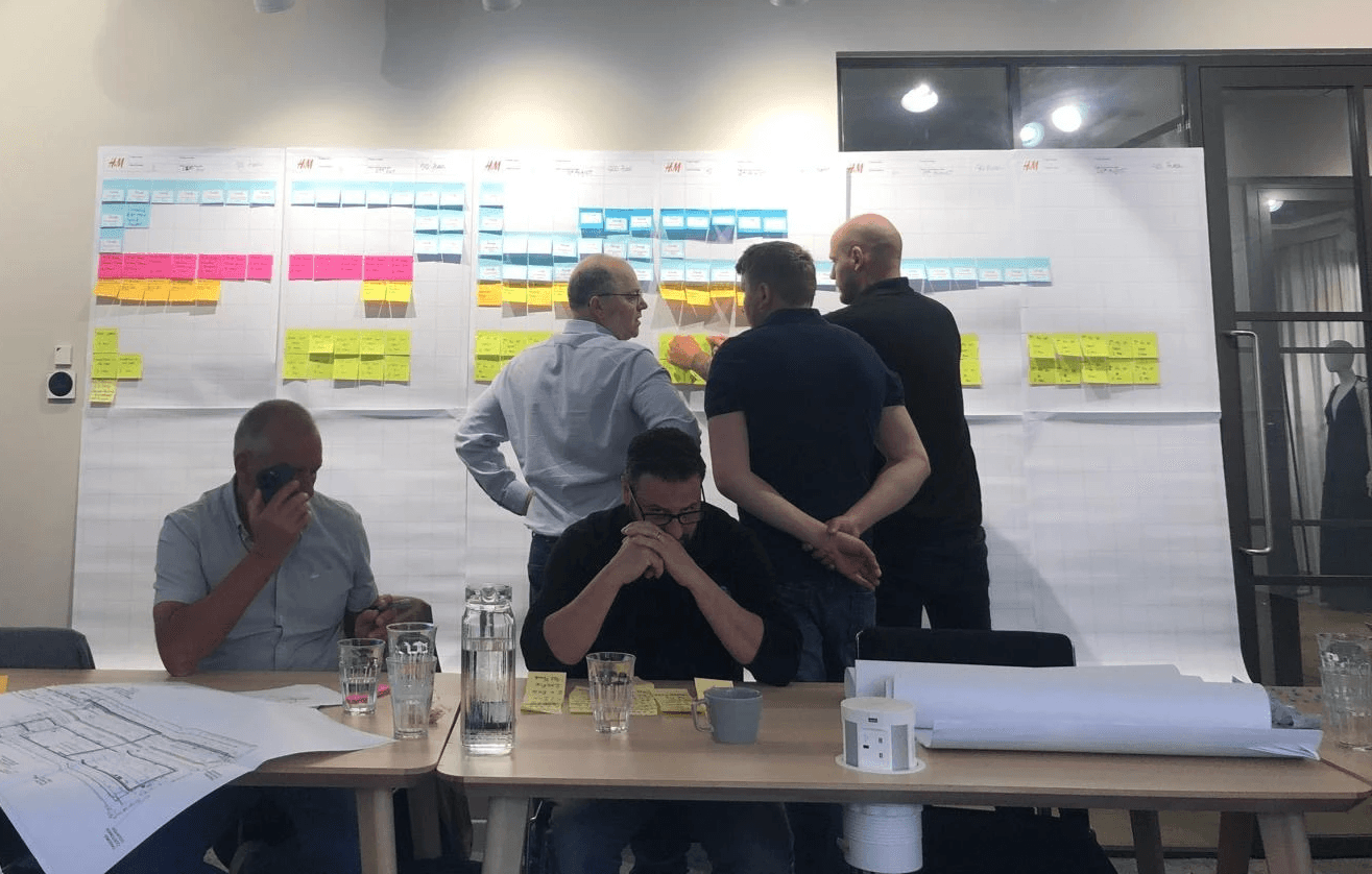 Four diverse professionals collaboratively working on a laptop, with one person pointing at the screen while others observe.