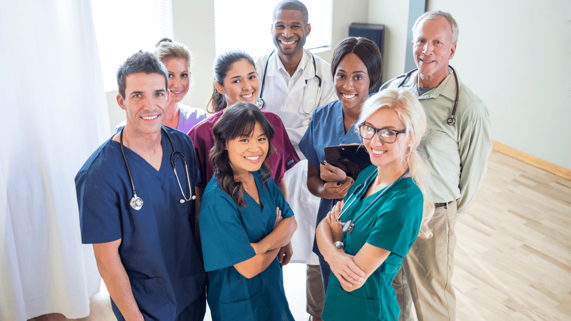 Group of medical doctors and nurses facing the camera and smiling.