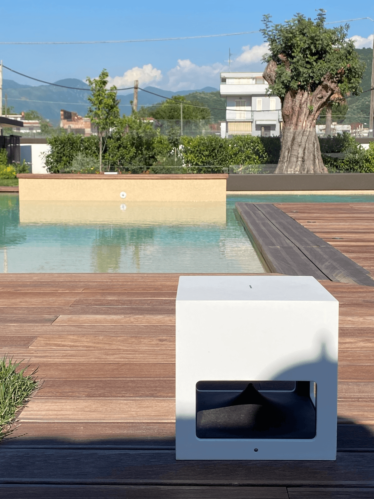 White cube on wooden deck near pool.