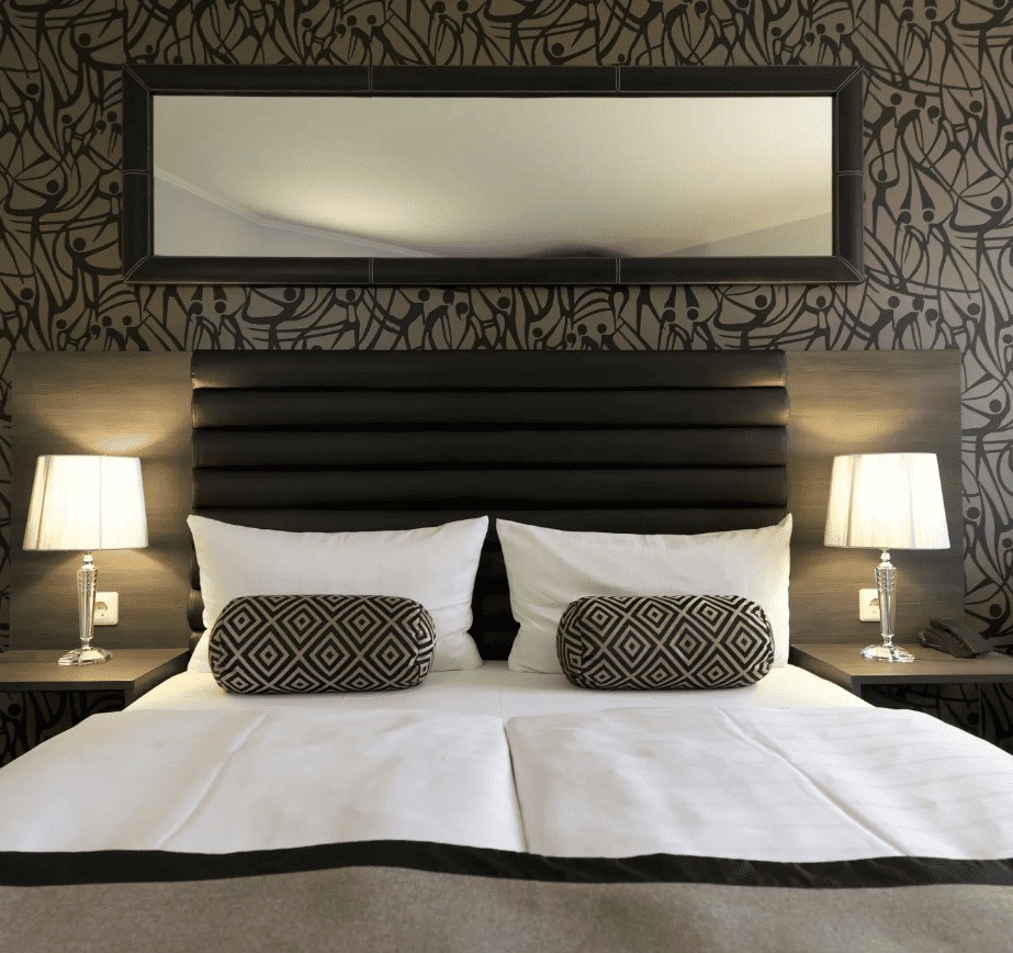 Frisch gemachtes Doppelbett mit weißer bettwäsche und braunen Akzenten