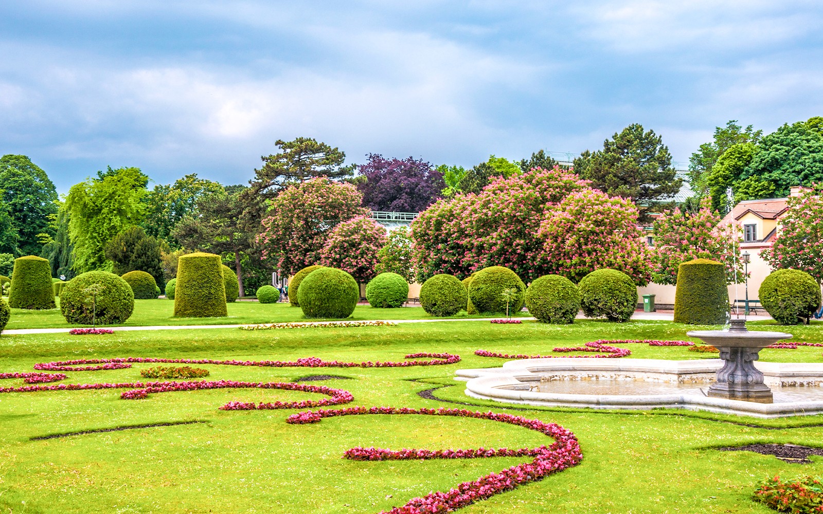 Ogrody pałacu Schönbrunn z przystrzyżonymi żywopłotami i ozdobną fontanną w Wiedniu.