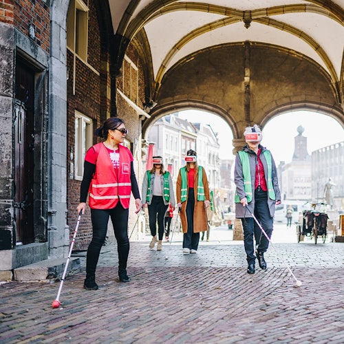 在探险山脊路线中，一位导游带领着几位游客。他们穿过奈梅亨市中心的一个拱门