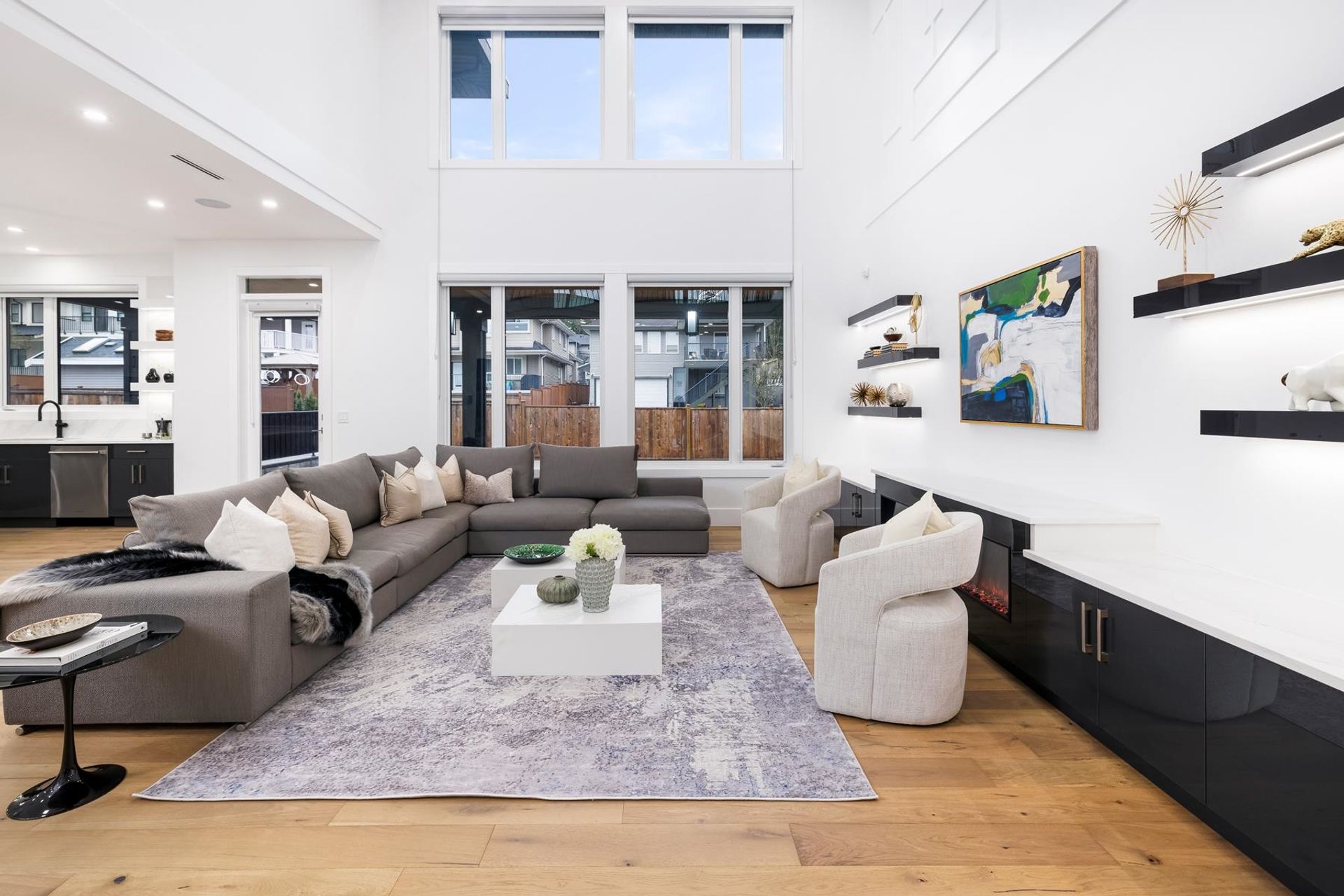Spacious modern living room with large windows, comfortable seating, and contemporary decor in neutral tones.