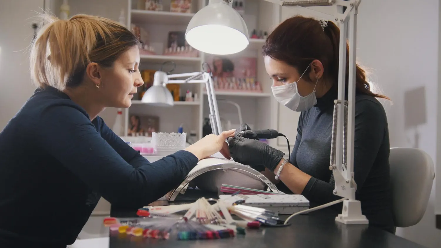 profissional fazendo a manicure da cliente usando um axilio de luz para melhor execução