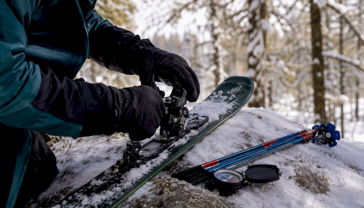 Ski guide repairing bindings outdoors in the snow