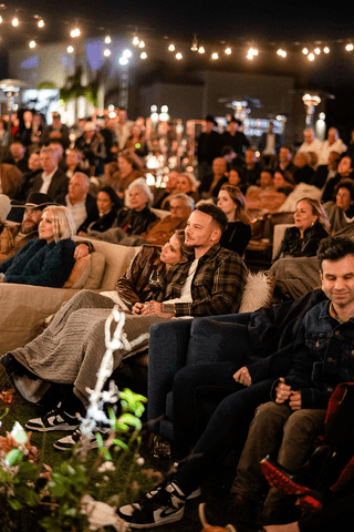A couple in wedding attire walks hand in hand across a sunlit field.