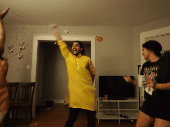 Friends throw their arms up in an exuberant living-room dance