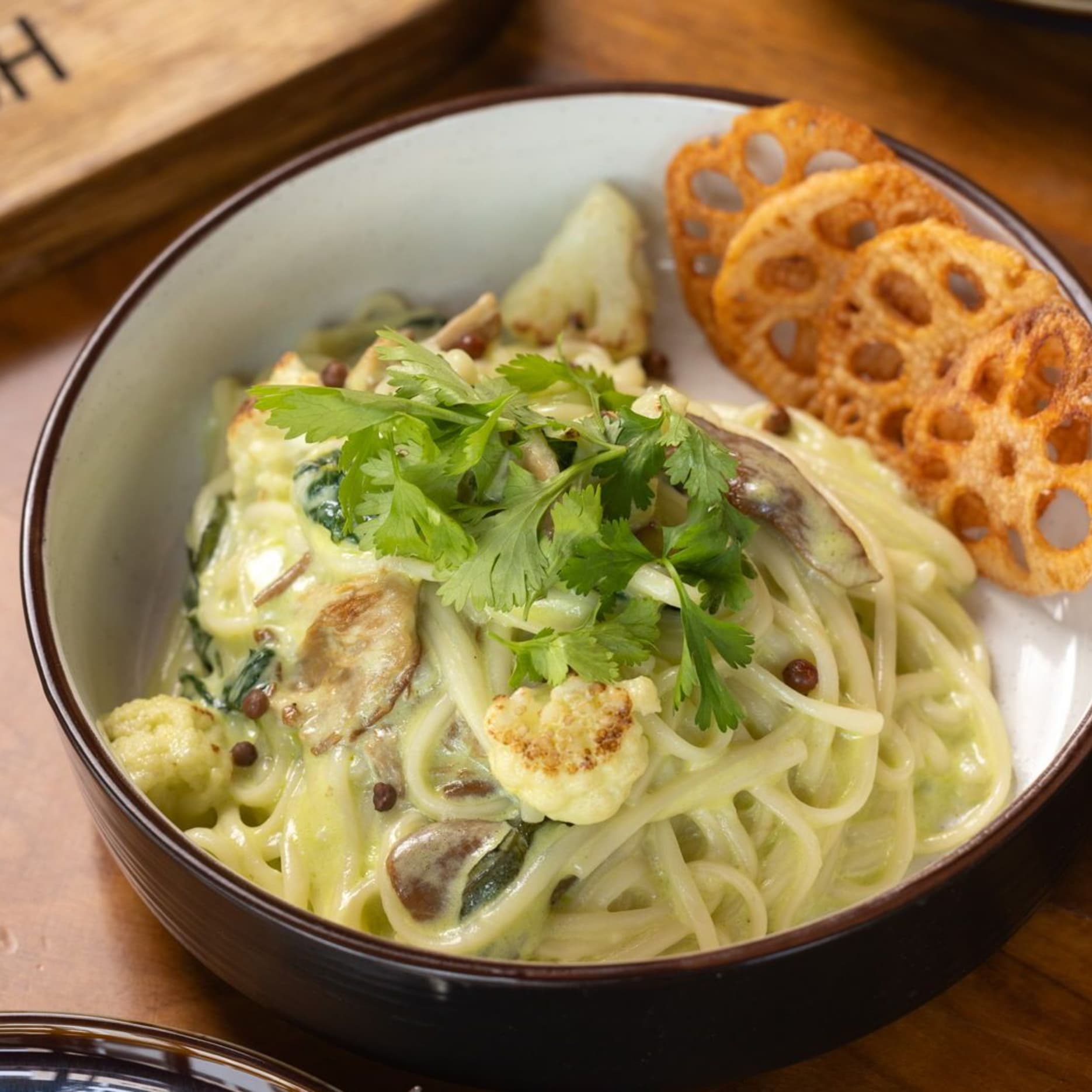 vegan food Banh Canh noodles with udon, mushrooms, cauliflower, lotus chips and coconut coriander dip served fresh for sharing.