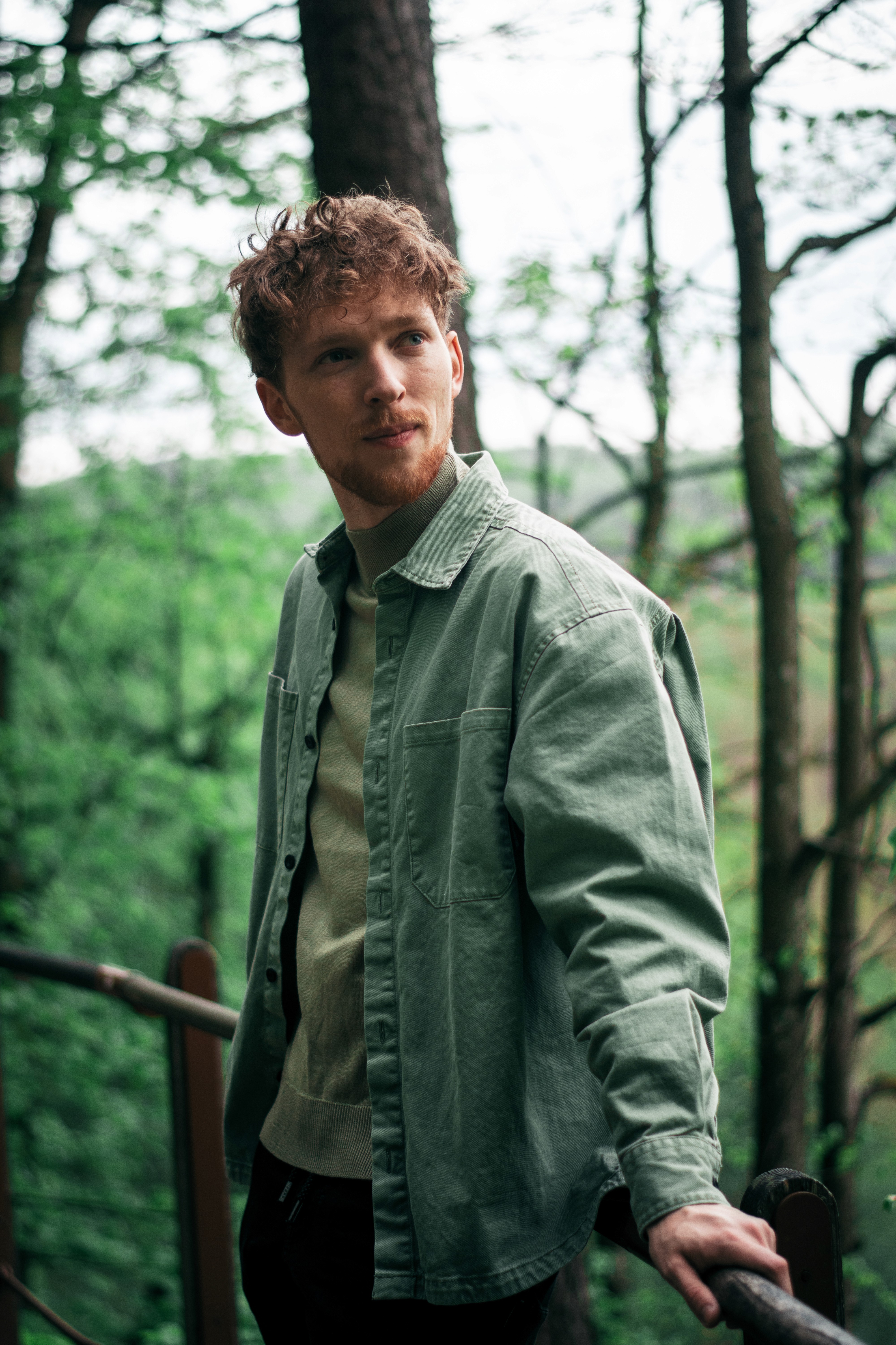 A person with shoulder-length blonde hair wearing a black newsboy cap and a black sweater.