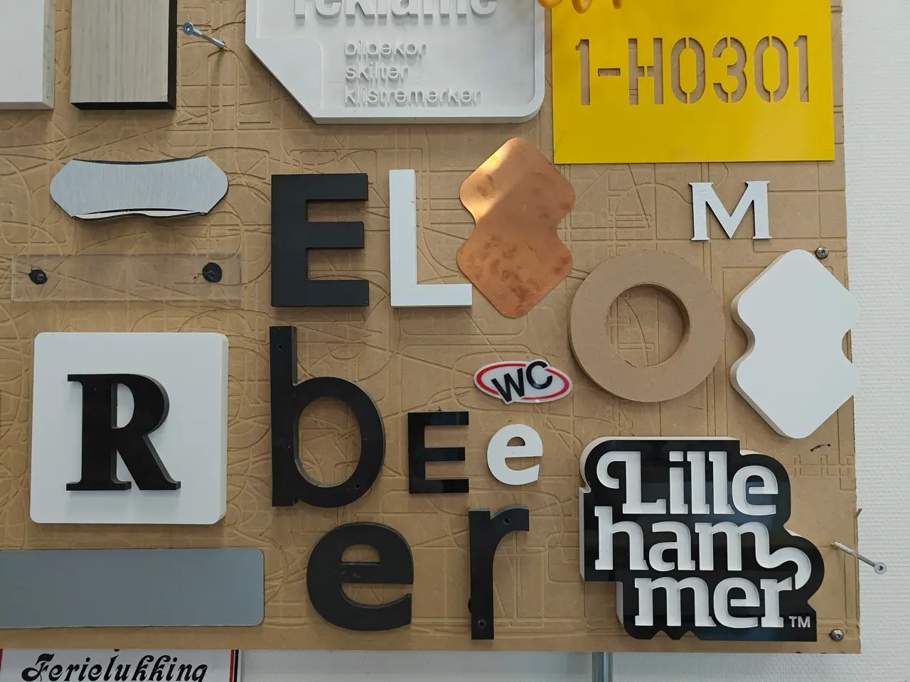 En utstilling av ulike materialer og typografier med forskjellige bokstaver og logoer, inkludert “Lillehammer” arrangert på en teksturert tavle.