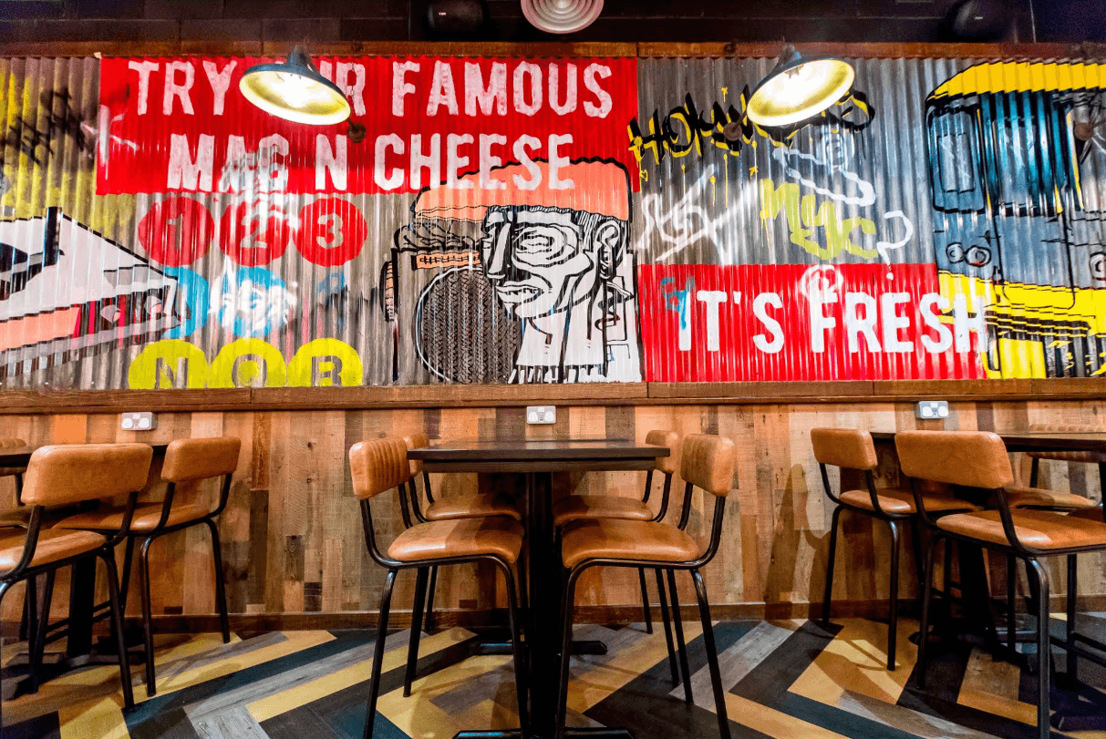 Holy Moly Macaroni restaurant fit-out with Harlem-inspired wall graphics, booth seating and branded interior finishes by Matrix IDC
