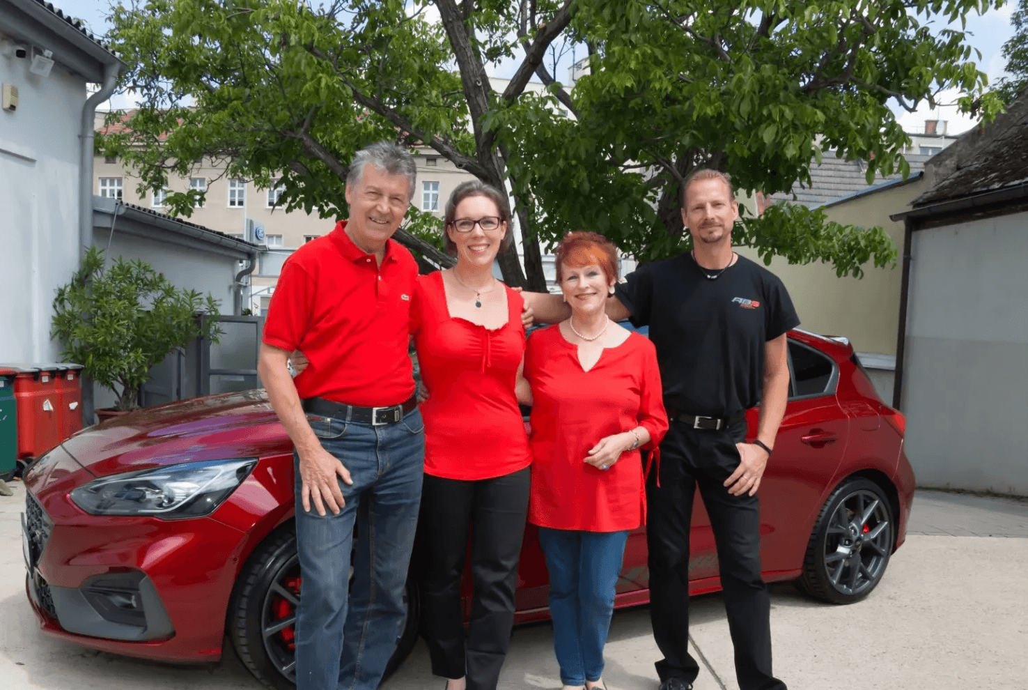 Familie Baumgartner vor einem roten Auto