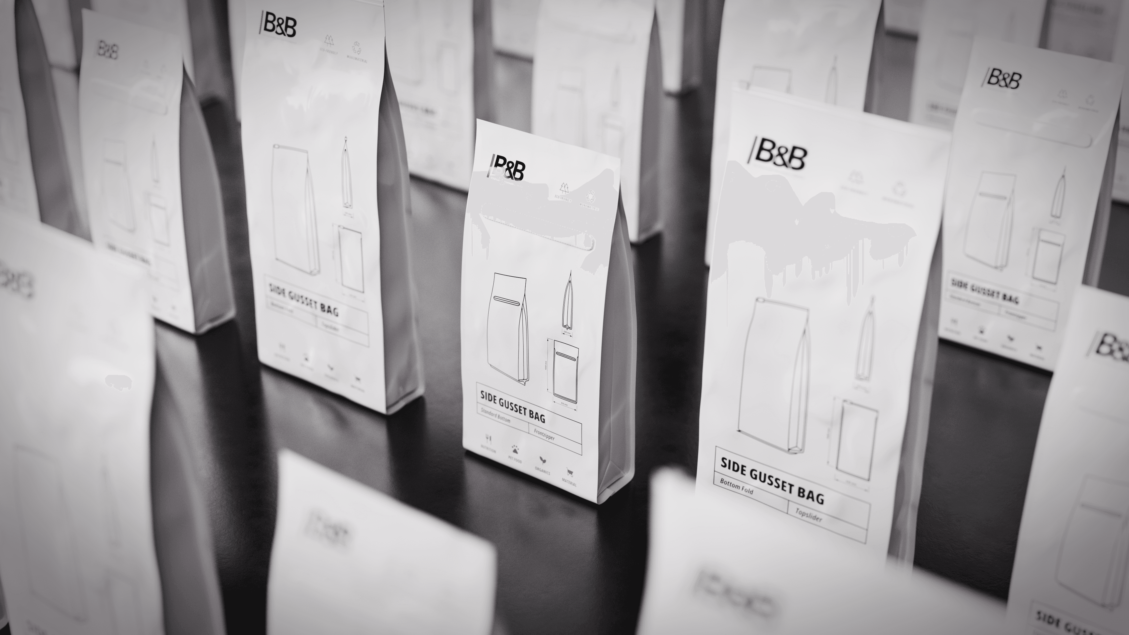 Kaffeeverpackungen in Schwarzweiß: Viele Beutel mit B&B-Logo und Produktnamen. Für Kaffee oder ähnliches verpackt.