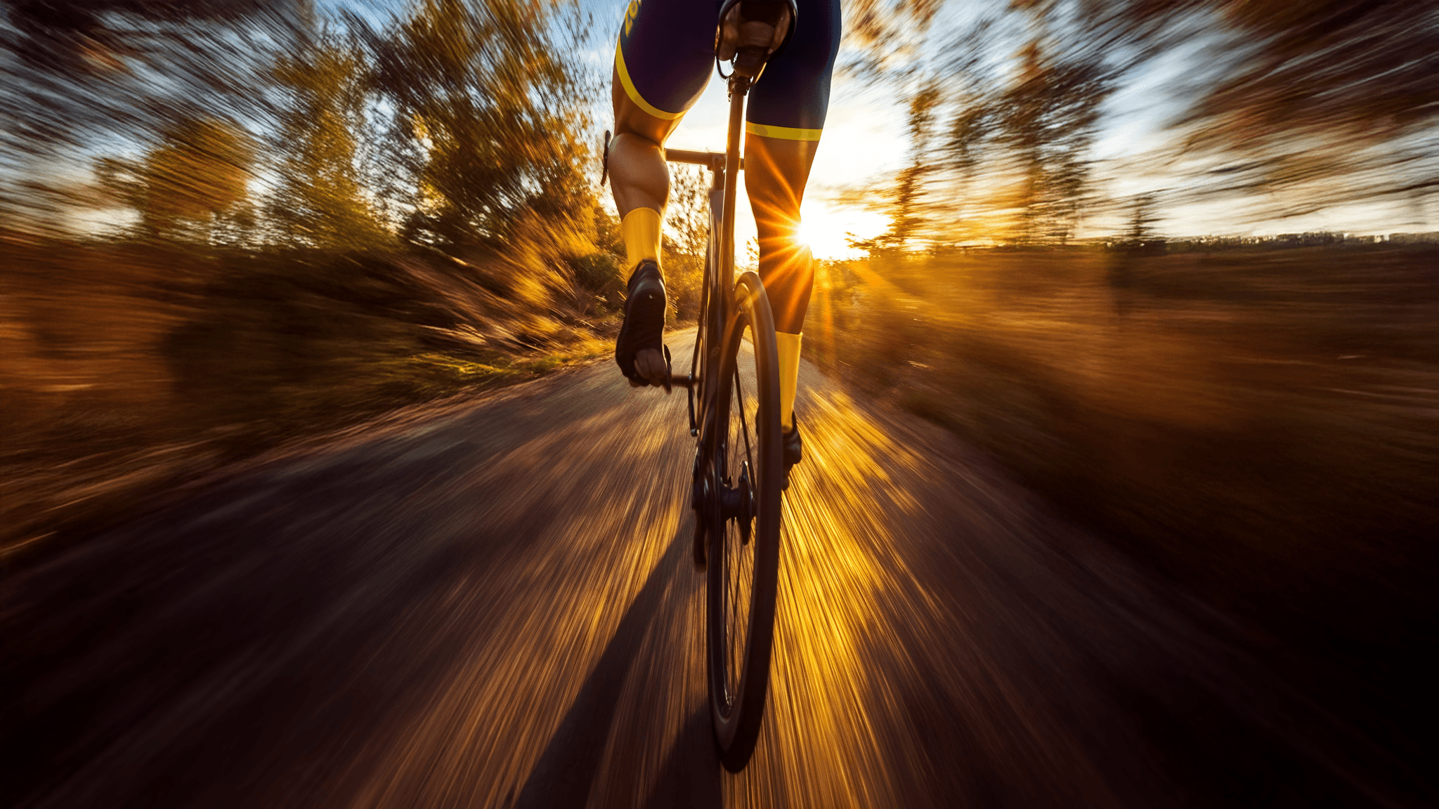 Ciclista en uniforme de zenbike rodando al amanecer, envuelto en luz dorada y velocidad. Profesionalismo y enfoque.