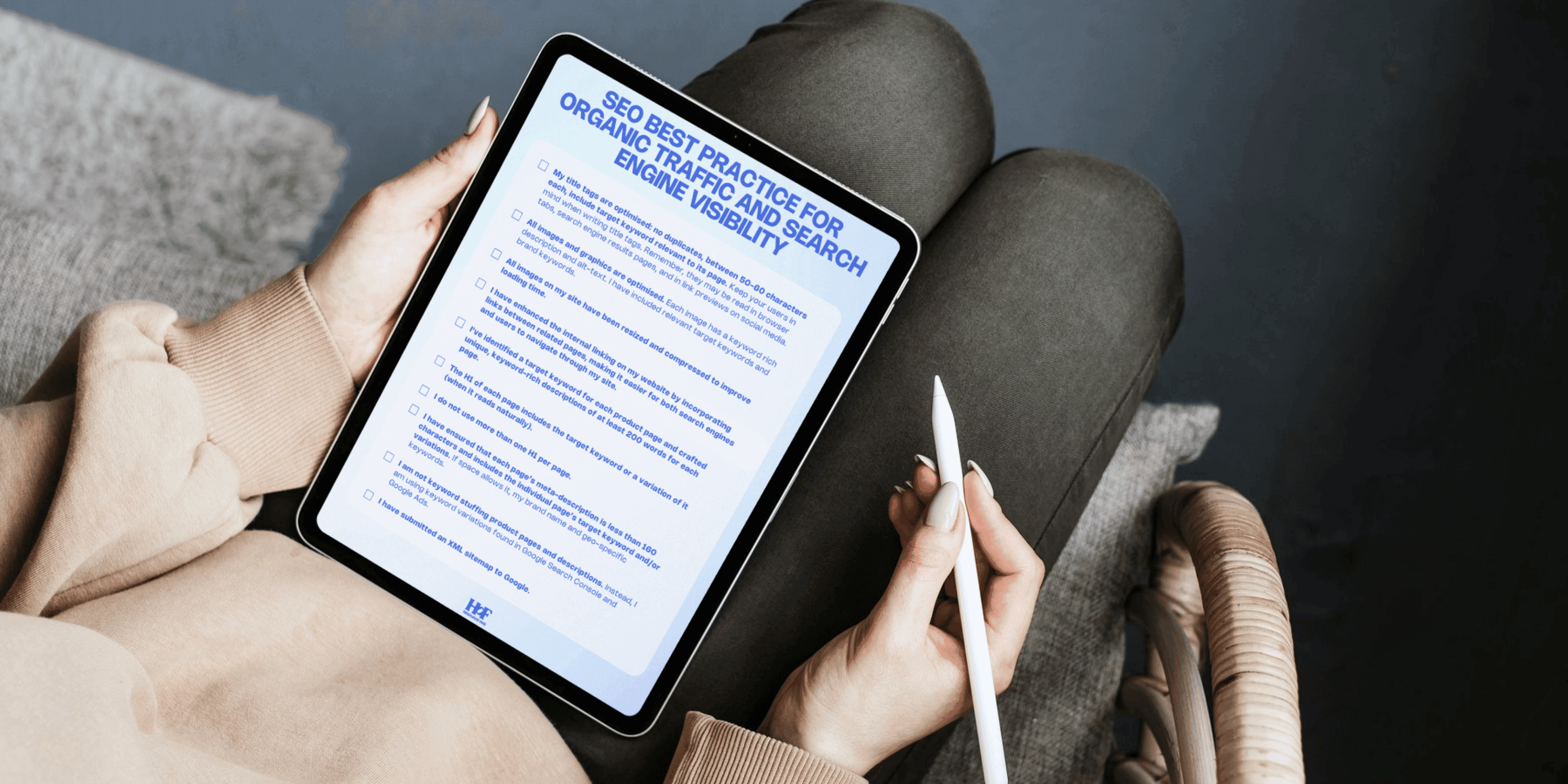 Image shows SEO checklist on tablet held in two hands over someone's lap.