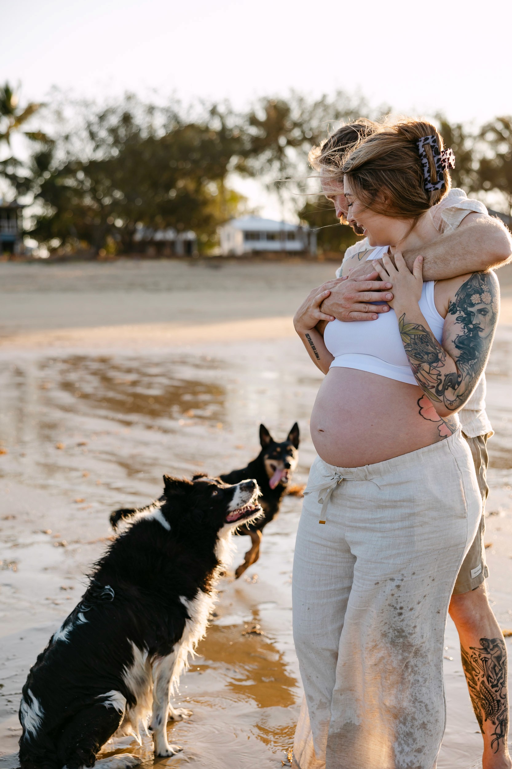 Couple with their dogs on the beach for a maternity photoshoot