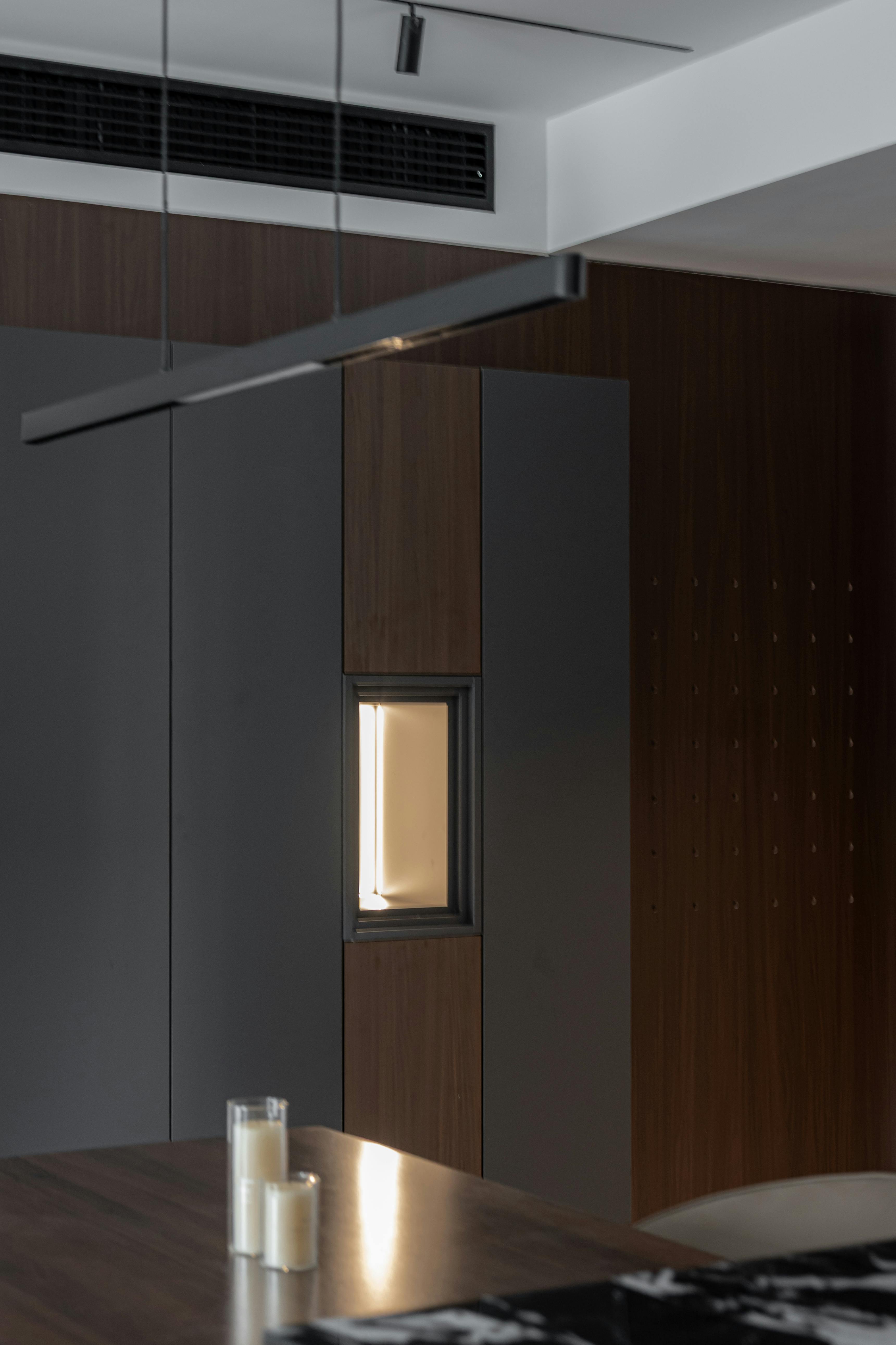 A modern kitchen and living room with white cabinets, herringbone floors, and a gray sectional sofa.