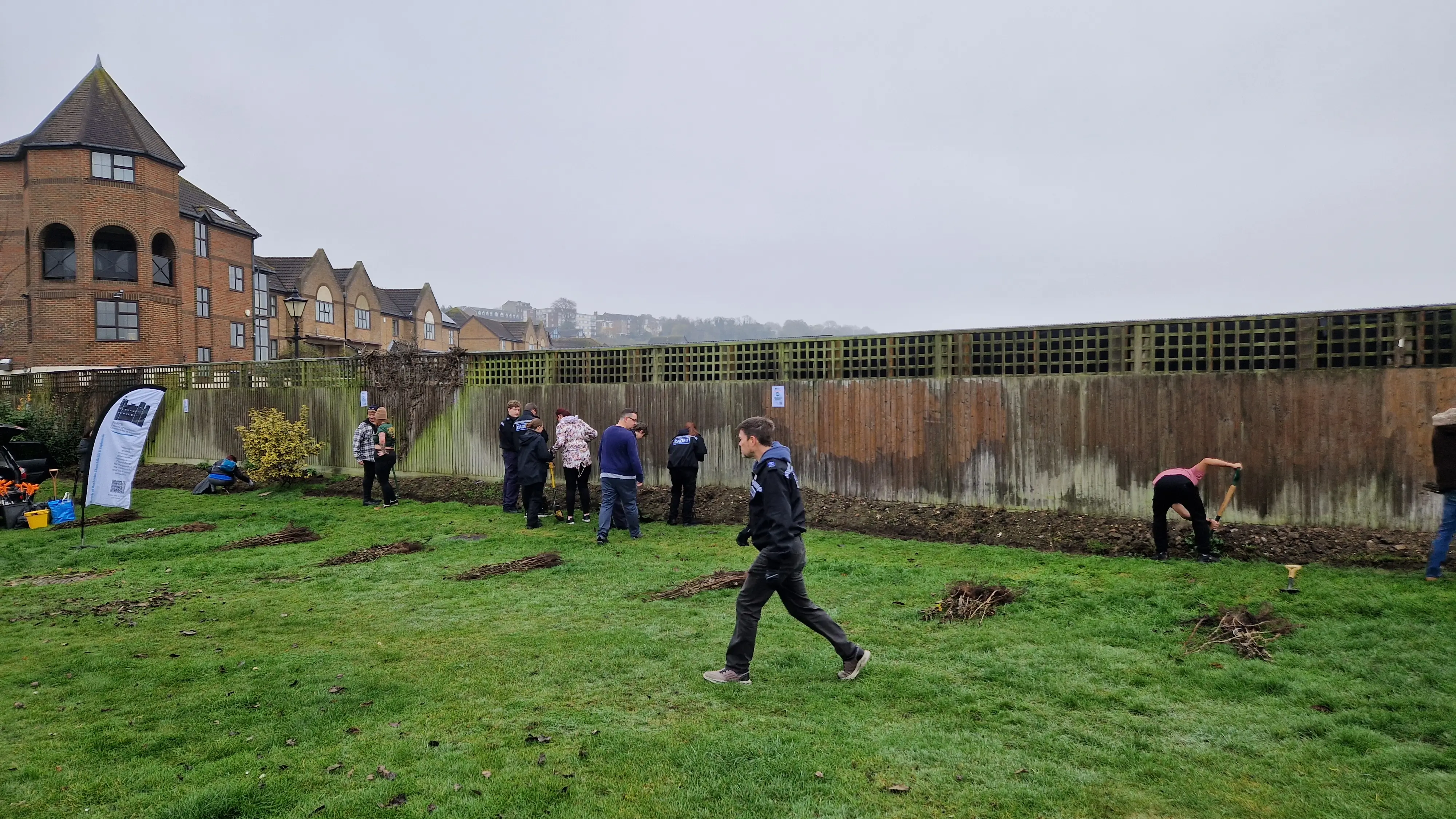 A group of people walking in a grassy area near a historical building under a cloudy sky.