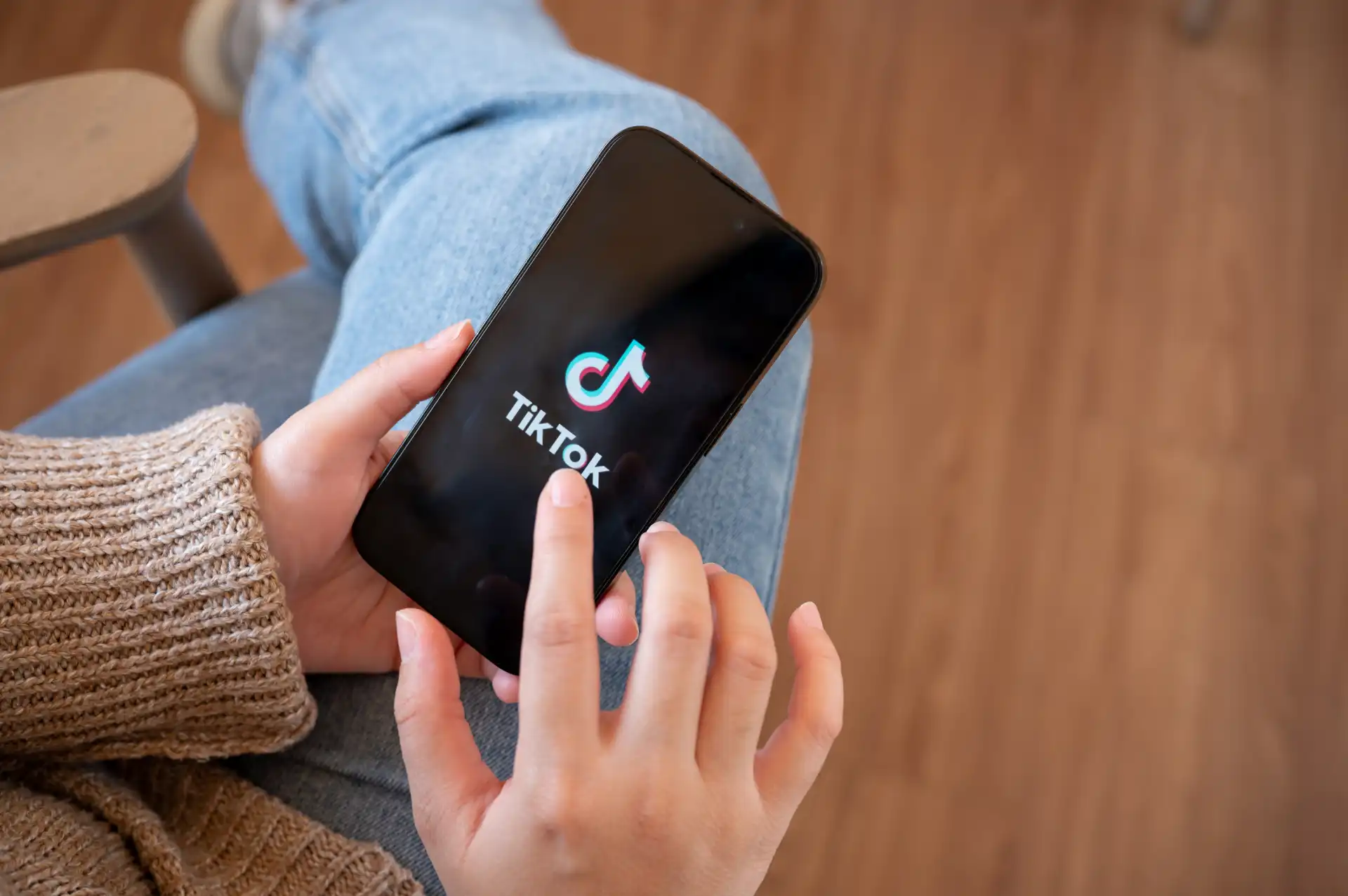 Person holding smartphone with TikTok app open, representing how the algorithm recommends content to users