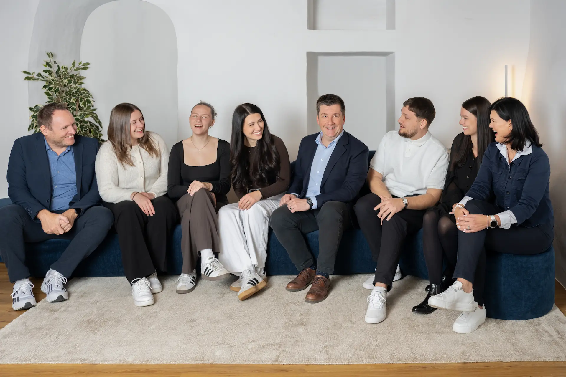 Gesamtes Team von Kocher Immobilien sitzt gemeinsam im Büro und lacht in moderner Umgebung