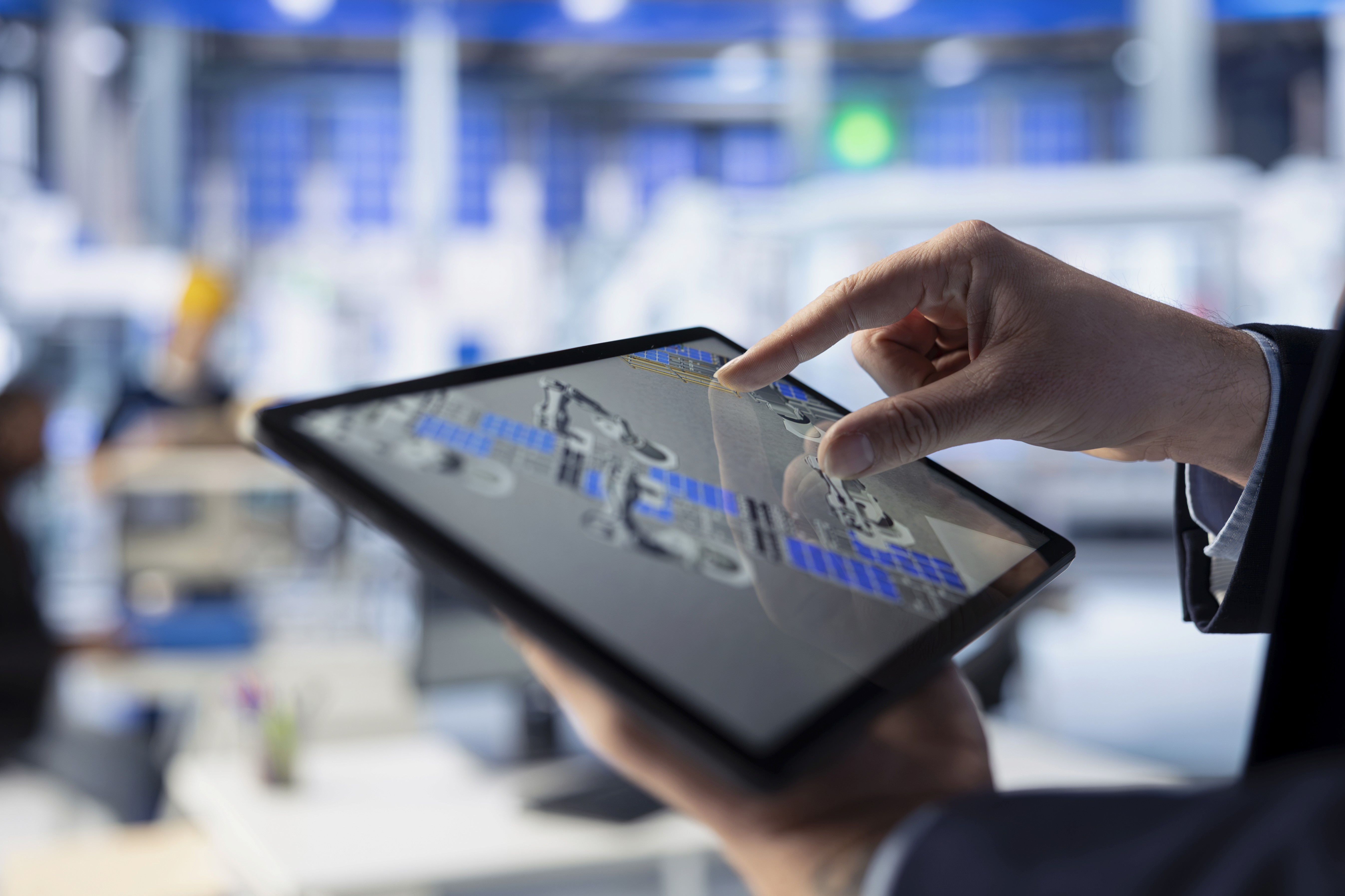 Hand tippt auf Tablet mit technischer 3D-Visualisierung in einem modernen Büro