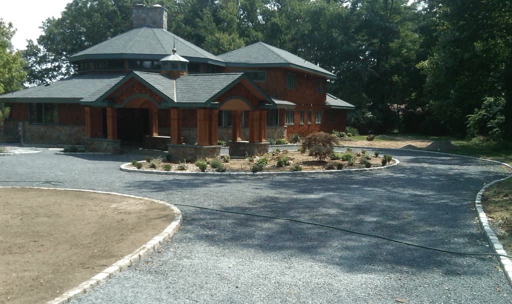 gravel driveway with planter island in front of brown house