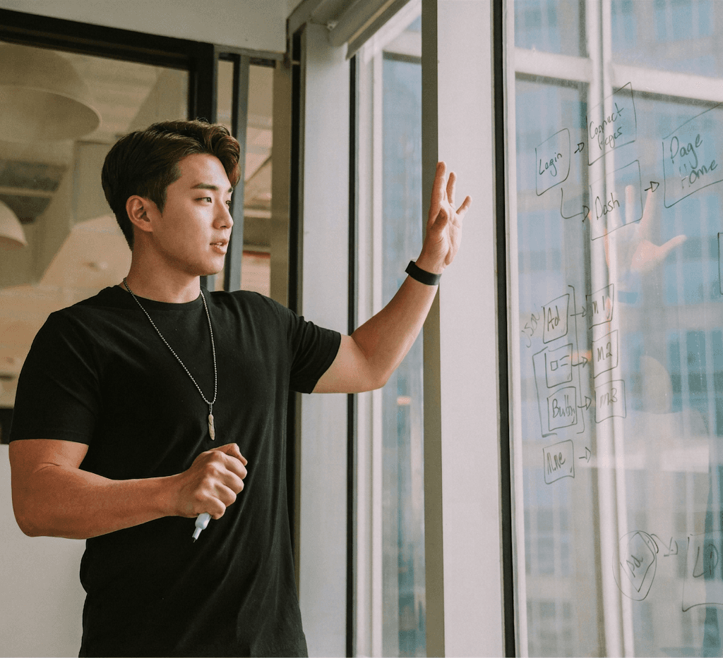 man in black shirt standing beside glass wall with written texts