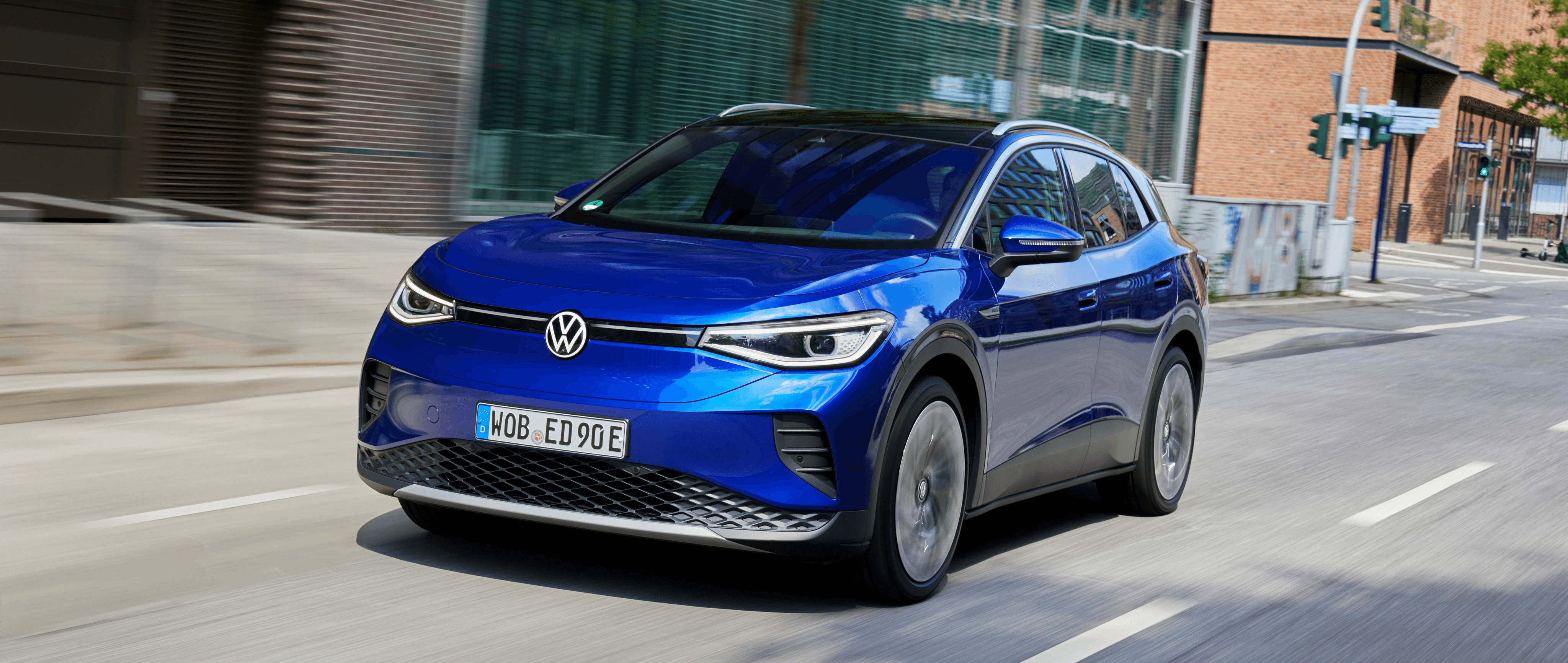 Volkswagen ID.4 bleue en mouvement en ville, vue avant trois quarts dans un environnement urbain