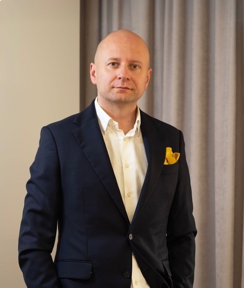 Przemysław Kamiński w granatowym garniturze z żółtą poszetką