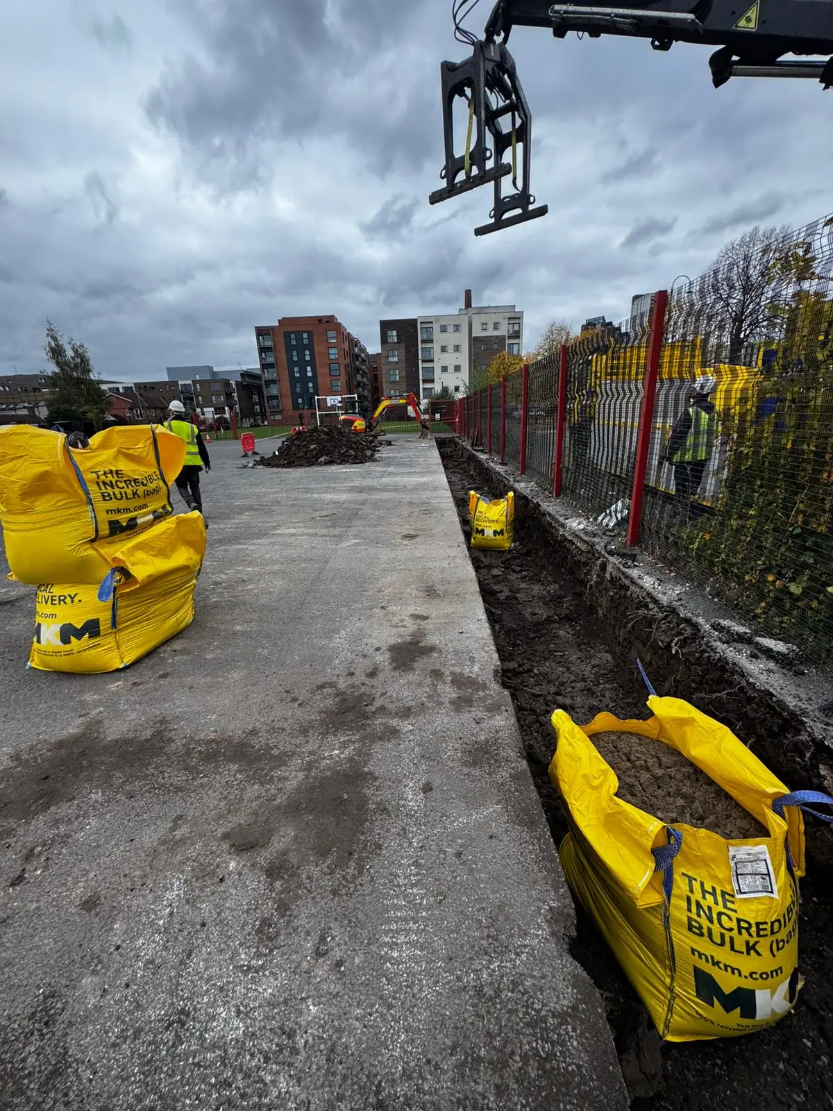 A construction site with yellow safety barriers and equipment under a cloudy sky, indicating active work.