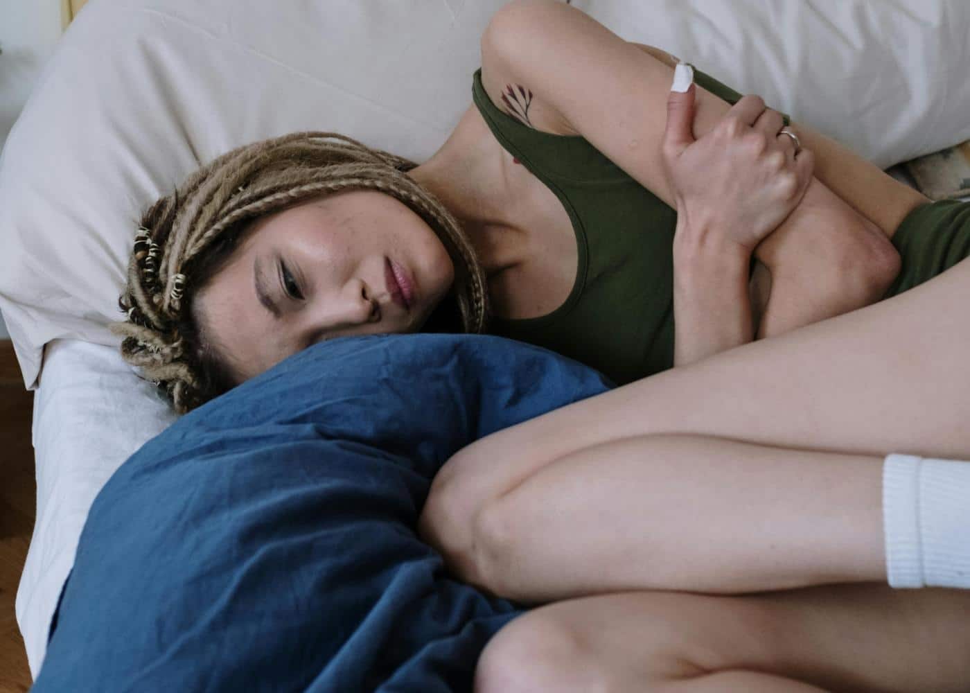 Woman trying to sleep while holding her gut in discomfort