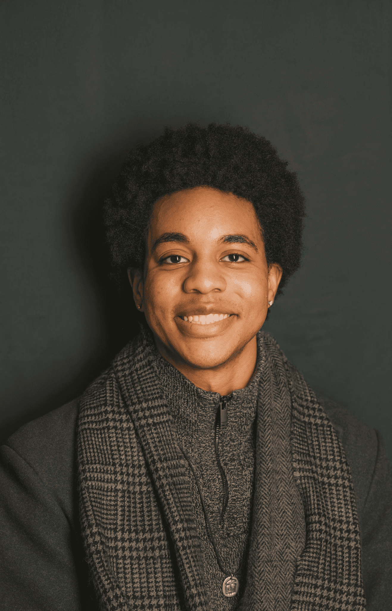 A thoughtful young person with dark hair gazes to the side, captured in soft black and white lighting.